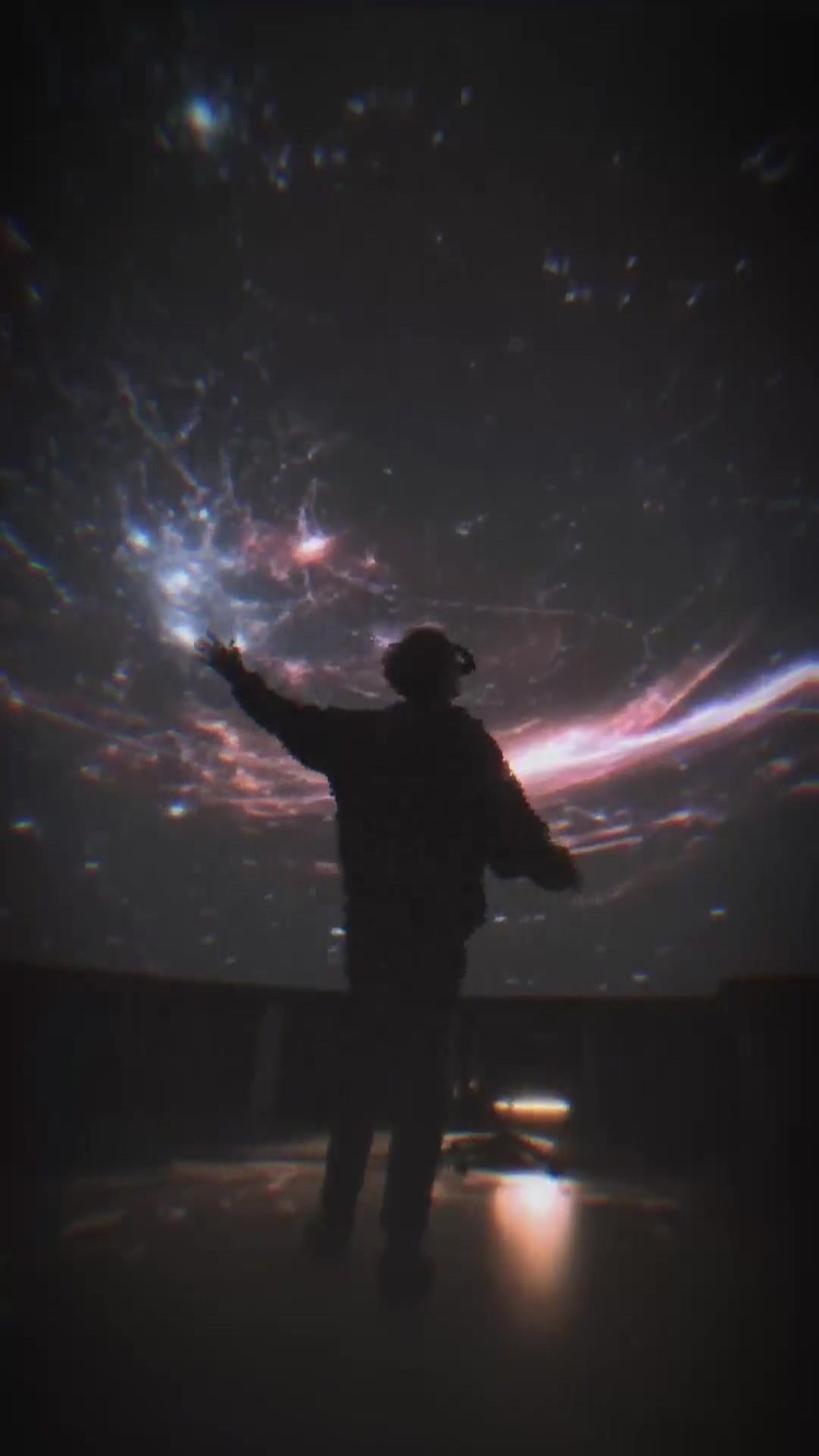 Silhouette viewing an immersive cosmic projection in the Effective Accelerationism technology video series